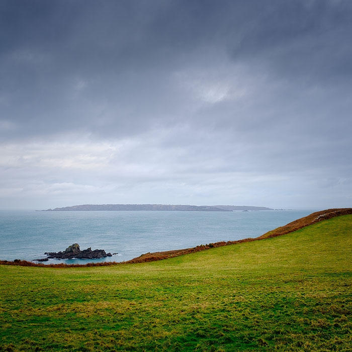 View across a Herm field looking toward Sark on a stormy day.