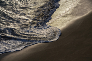 Sunlight glistens on waves and sand at Belvoir Bay.