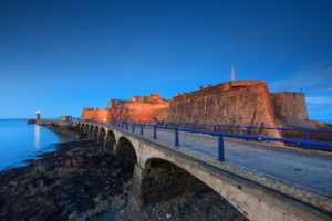 Castle Cornet and breakwater illuminated at dusk.