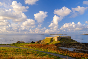 Fluffy clouds pass over Fort Pezeries, bathed in late evening light.