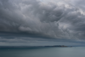 A lone yacht sails below a foreboding storm cloud in the Little Russell.