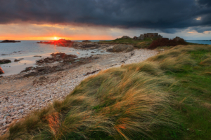 Sun setting below storm clouds at a windy Grandes Rocques.