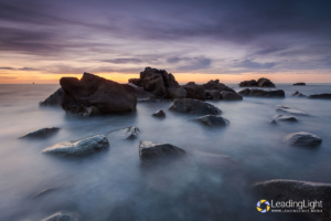Rising tide surrounds rocks near Pulias on Guernsey's west coast as the light of dusk fades.