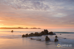 A rising tide and dramatic sky over L'Ancresse Bay, Guernsey at sunset.