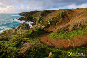 A path meanders through a valley and around Guernsey's south coast cliffs.
