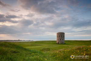 A Loophole tower on L'ancresse common with wildflowers in the foreground.