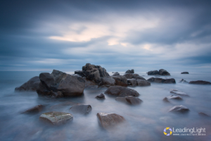 Smooth water surrounds rocks in this calming blue scene near Pulias, Guernsey.