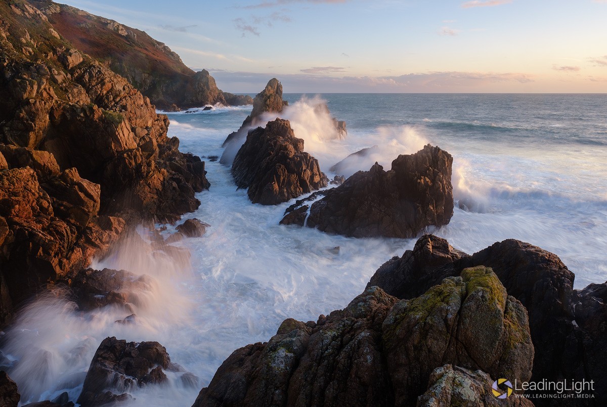 Heavy waves crash against rocks at Le Jaonnet Bay, Guernsey at sunset